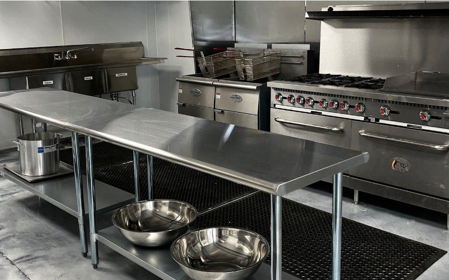 The teaching kitchen with a steel prep table, stove and sinks