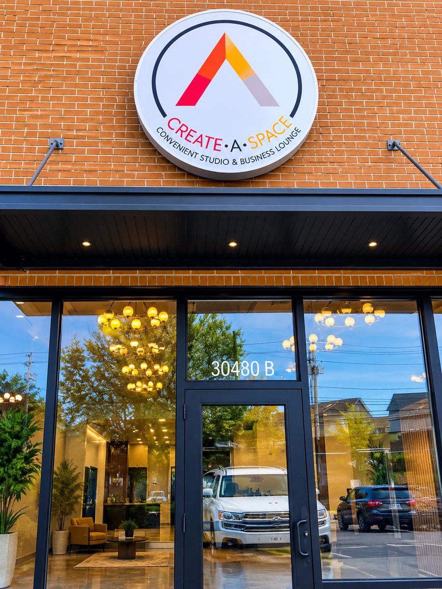 The Create A Space storefront with its round sign above a glass door, on a brick building